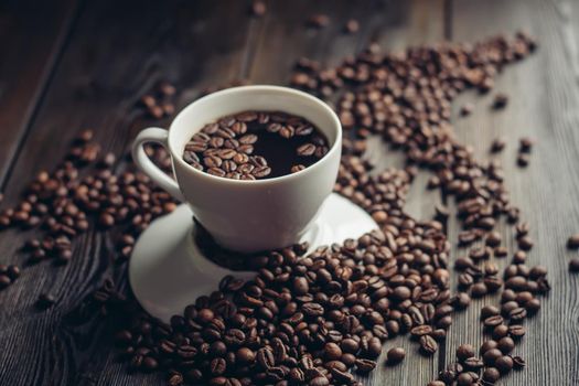 coffee beans on a wooden background and a cup on a saucer close-up macro photography. High quality photo