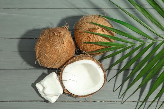 Coconuts with palm branch on wooden table, space for text