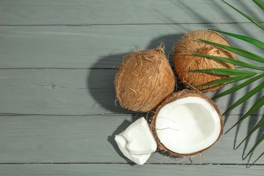 Coconuts with palm branch on wooden table, space for text