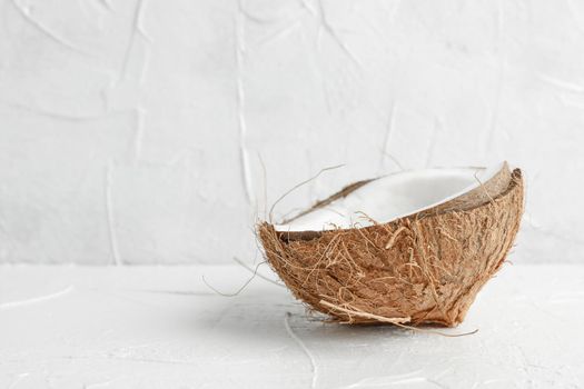 Half tropical coconut on wooden table against white background, space for text