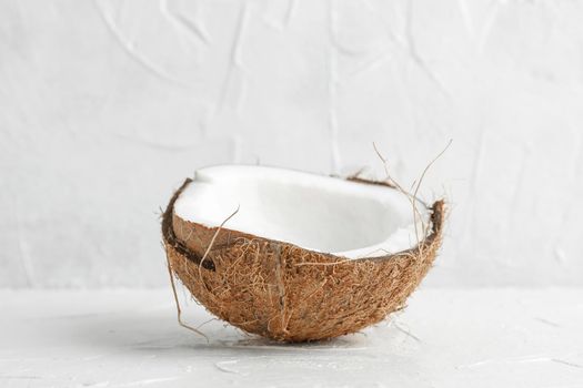 Half tropical coconut on wooden table against white background, space for text