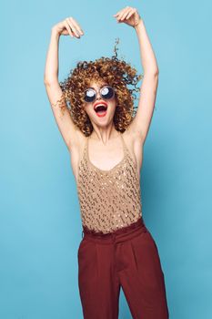 Charming model Curly hair dark glasses red lips fashionable clothes red pants blue isolated background