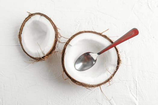 Half coconut with spoon on white background, space for text