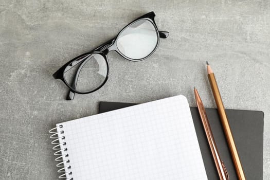 Copybooks, glasses and pencil on grey table, space for text