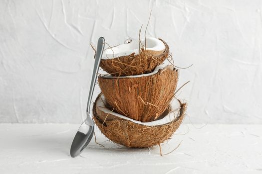 Stack tropical coconut with spoon on wooden table against white background