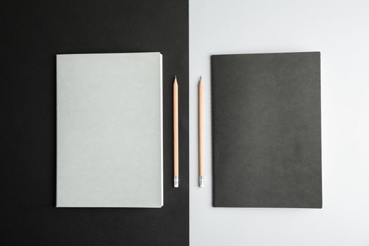 Copybooks with pencils on two tone background, top view