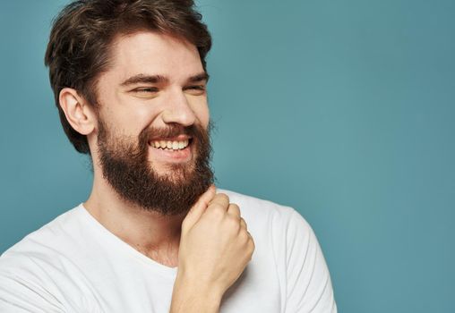 Portrait of a man blue background close-up cropped view white t-shirt handsome smile. High quality photo