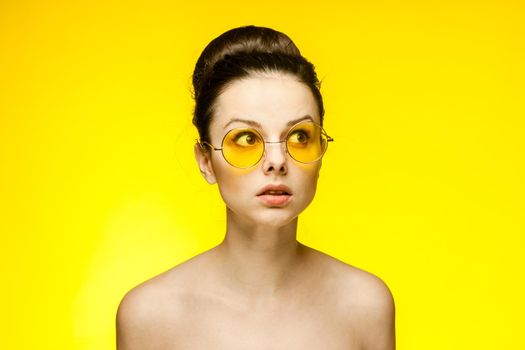 woman naked shoulders surprised look yellow glasses isolated background. High quality photo