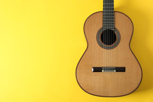 Beautiful classic guitar on yellow background, space for text