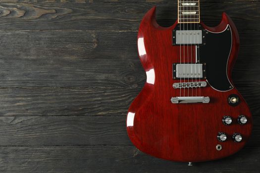 Beautiful six - string electric guitar on wooden background, space for text