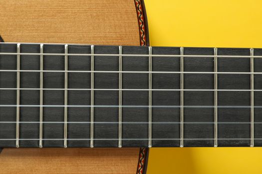 Guitar neck on yellow background, closeup