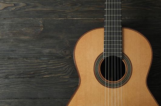 Beautiful six - string classic guitar on wooden background, space for text