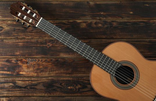 Beautiful six - string classic guitar on wooden background, space for text