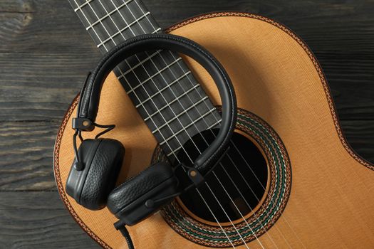 Beautiful classic guitar with headphones on wooden background, closeup
