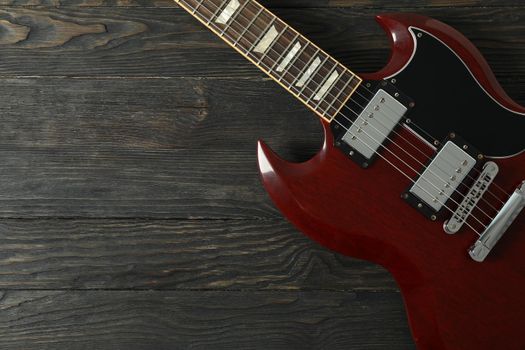 Beautiful six - string electric guitar on wooden background, space for text