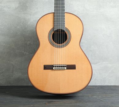 Beautiful six - string classic guitar on wooden table against grey background
