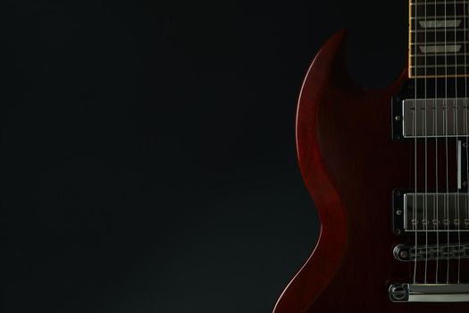 Beautiful six - string electric guitar against dark background, space for text