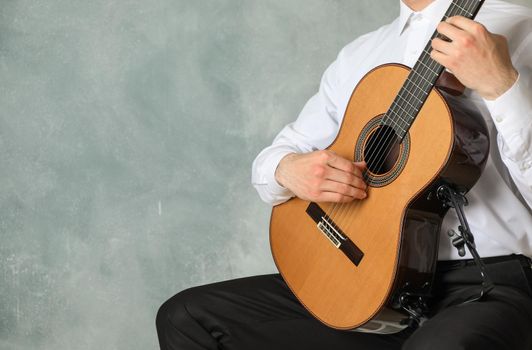 Man playing on classic guitar against light background, space for text