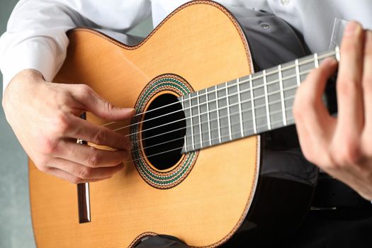 Man playing on classic guitar against light background, space for text