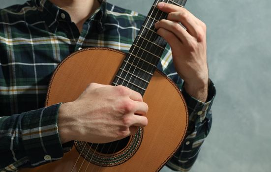 Man playing on classic guitar against light background