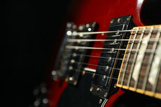 Beautiful six - string electric guitar against dark background, closeup