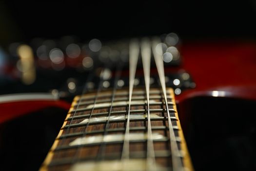 Beautiful six - string electric guitar against dark background, closeup