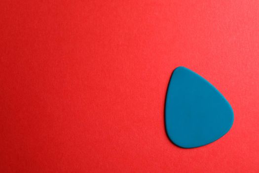 Blue guitar pick on color background, space for text