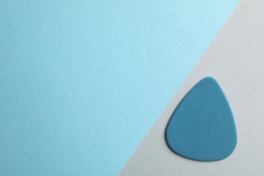 Blue guitar pick on two tone background, space for text