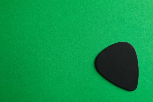 Black guitar pick on color background, space for text