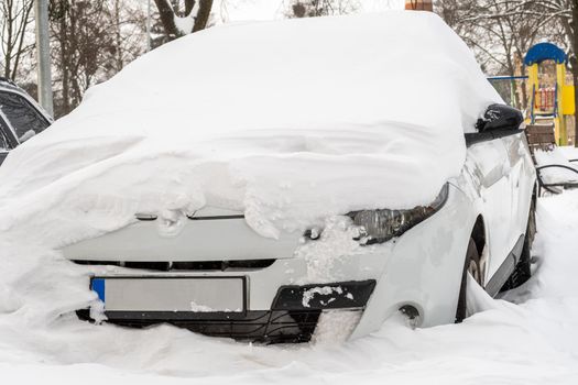 Stuck cars under the snow and ice. City street after blizzard. Buried vehicle in snowdrift on the road. Parking lots in winter after heavy snowfall. Uncleaned roads. Record-breaking amounts of snow.