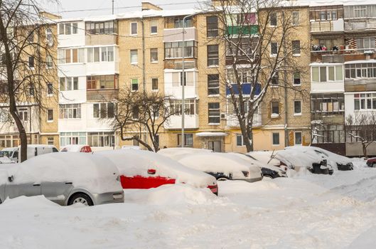 Stuck cars under the snow and ice. City street after blizzard. Buried vehicle in snowdrift on the road. Parking lots in winter after heavy snowfall. Uncleaned roads. Record-breaking amounts of snow.