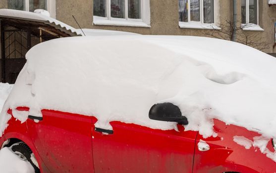 Stuck cars under the snow and ice. City street after blizzard. Buried vehicle in snowdrift on the road. Parking lots in winter after heavy snowfall. Uncleaned roads. Record-breaking amounts of snow.