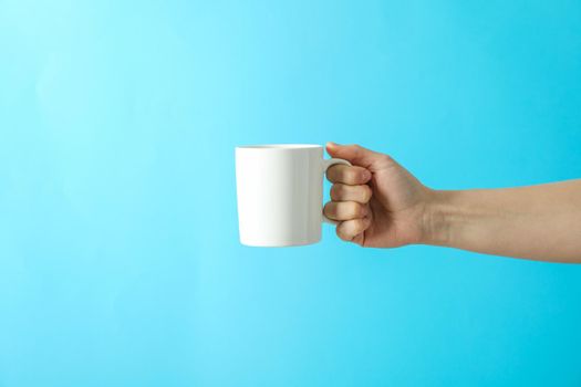 Female hand holding white cup against color background, space for text