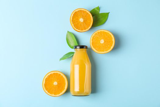 Flat lay composition with fresh orange juice in bottle and oranges with leaves on color background, space for text. Fresh natural drink