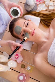 Young woman in spa health concept with face mask