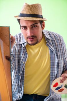 Young male artist working on new painting in his studio