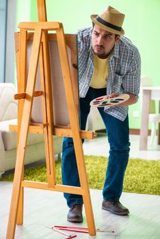 Young male artist working on new painting in his studio