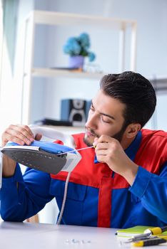 Man repairman repairing iron at service center