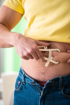 Young man measuring body fat with calipers 