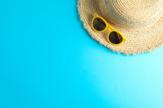 Straw hat and sunglasses on color background, space for text