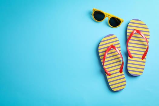 Sunglasses and flip flops on color background, space for text