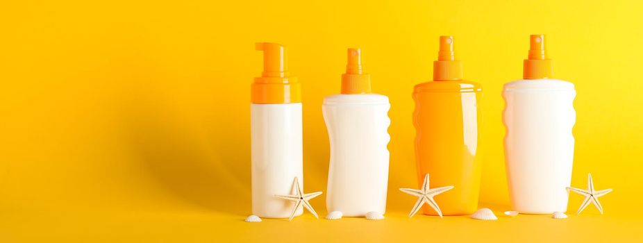 Sunscreen sprays with starfishes on color background, space for text. Safe tan accessories