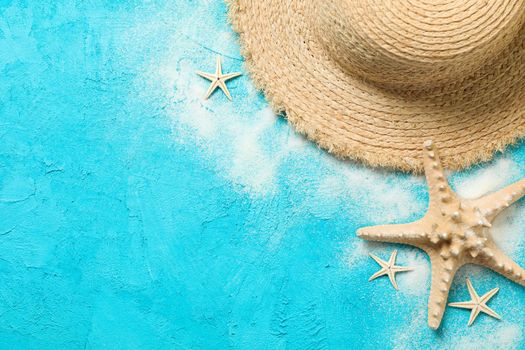 Straw hat, sand and starfish on color background, space for text. Summer vacation backdrop