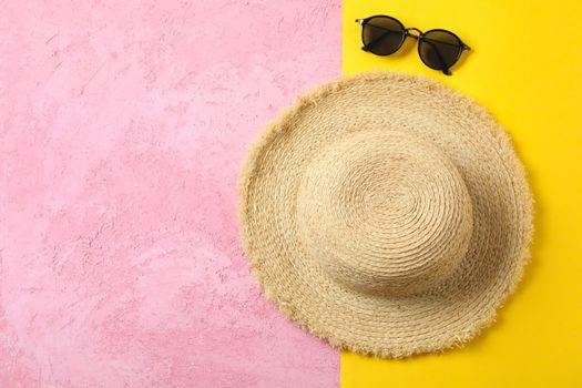 Straw hat and sunglasses on two tone background, space for text and top view. Summer vacation backdrop