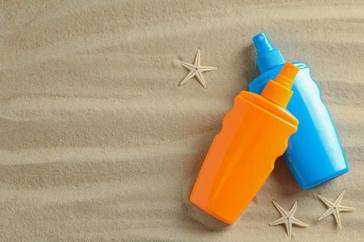 Clear sea sand with starfish and sunscreens, space for text. Summer vacation background