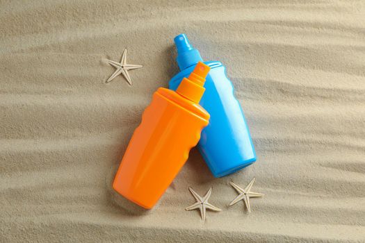 Clear sea sand with starfish and sunscreens, space for text. Summer vacation background