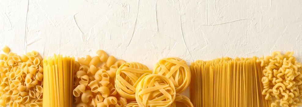 Different pasta on white background, space for text. Dry uncooked whole pasta