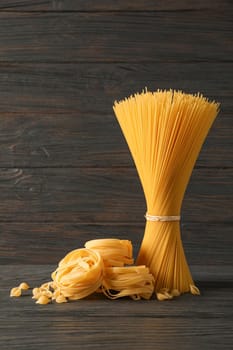 Pasta composition on wooden table, space for text. Dry raw whole pasta