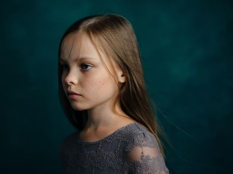 Little girl in a gray dress on a green background close-up cropped view. High quality photo