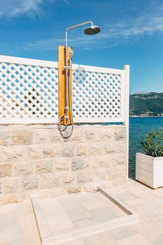 Open-type shower cabin, outside, near the sea. Shower watering can after swimming in the sea
